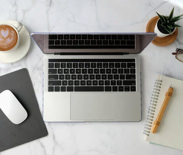 Laptop surrounded by notepad and pen and a mouse